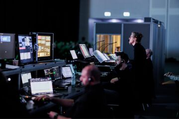 Crew in the control room monitoring the Hybrid Event with laptops, mixing consoles, and displays